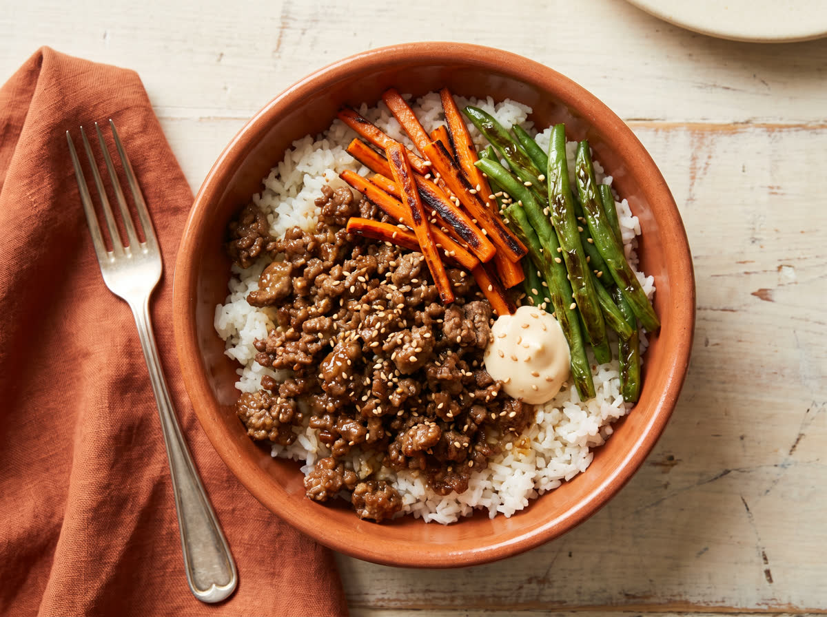 Overhead photo of Korean-style beef bowl with garlic rice, charred carrot and green beans, and sesame mayo